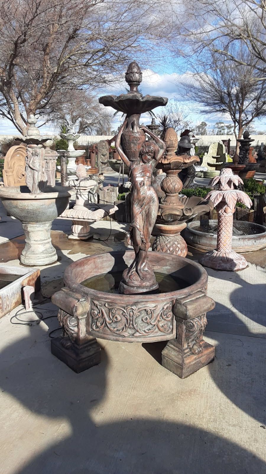 Decorative stone fountain with ornate basins and sculpted figures in an outdoor garden under bare trees