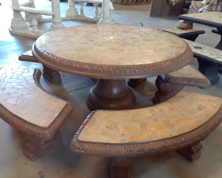Round mosaic stone table with curved benches in a rustic outdoor seating area