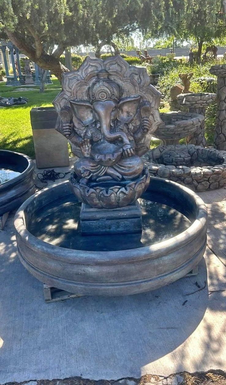 Stone lion fountain in a park, with water basin and trees in the background