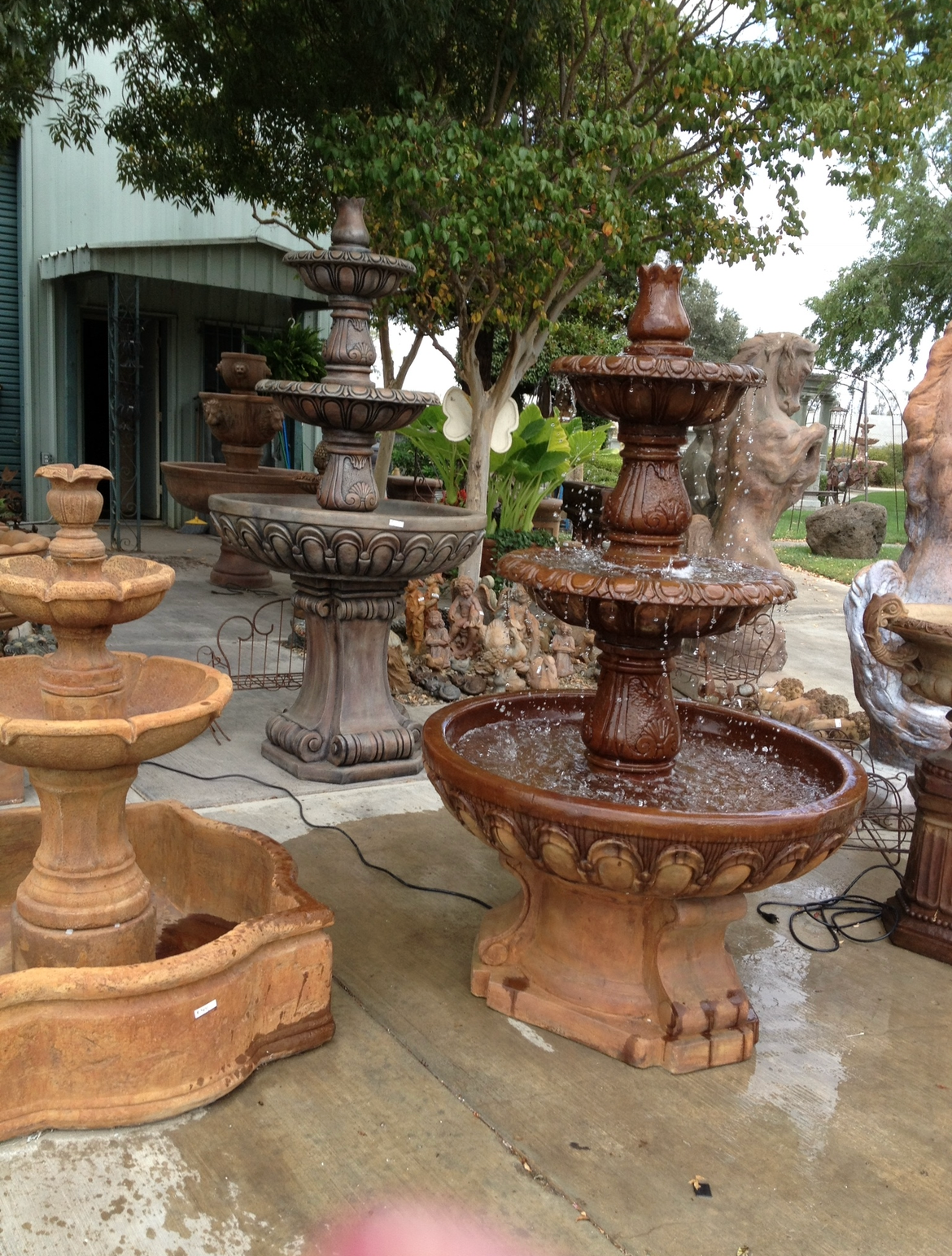 Decorative stone fountains in an outdoor garden, including a brown tiered fountain in front