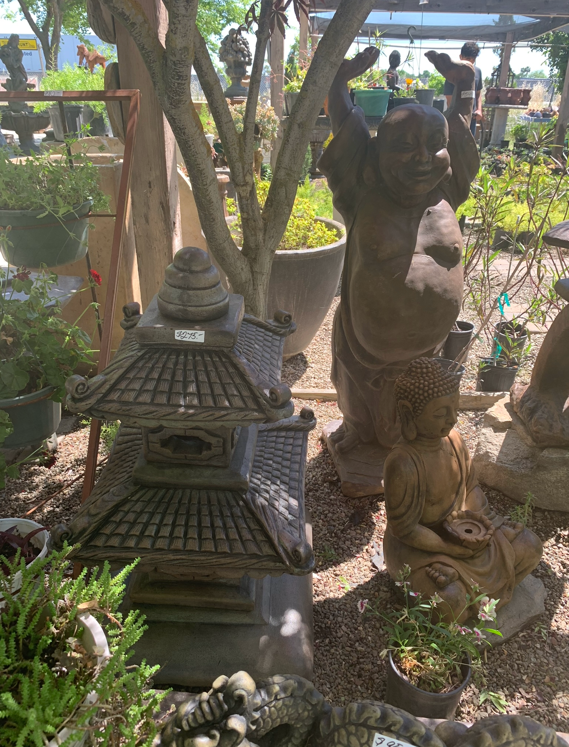 Garden with stone pagoda lantern, bear statue, and potted plants in sunlight