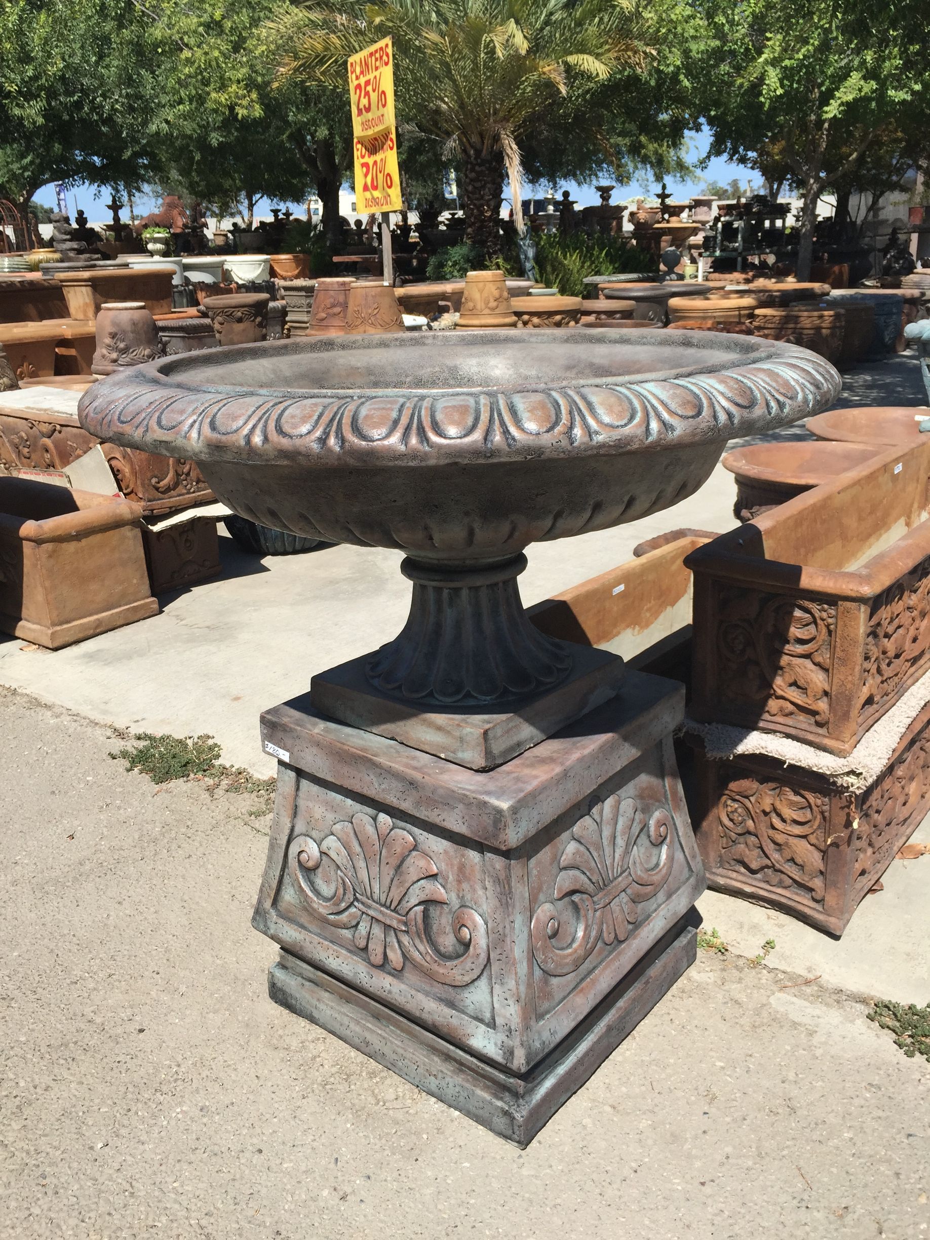 Ornate stone planter on a pedestal in an outdoor patio display