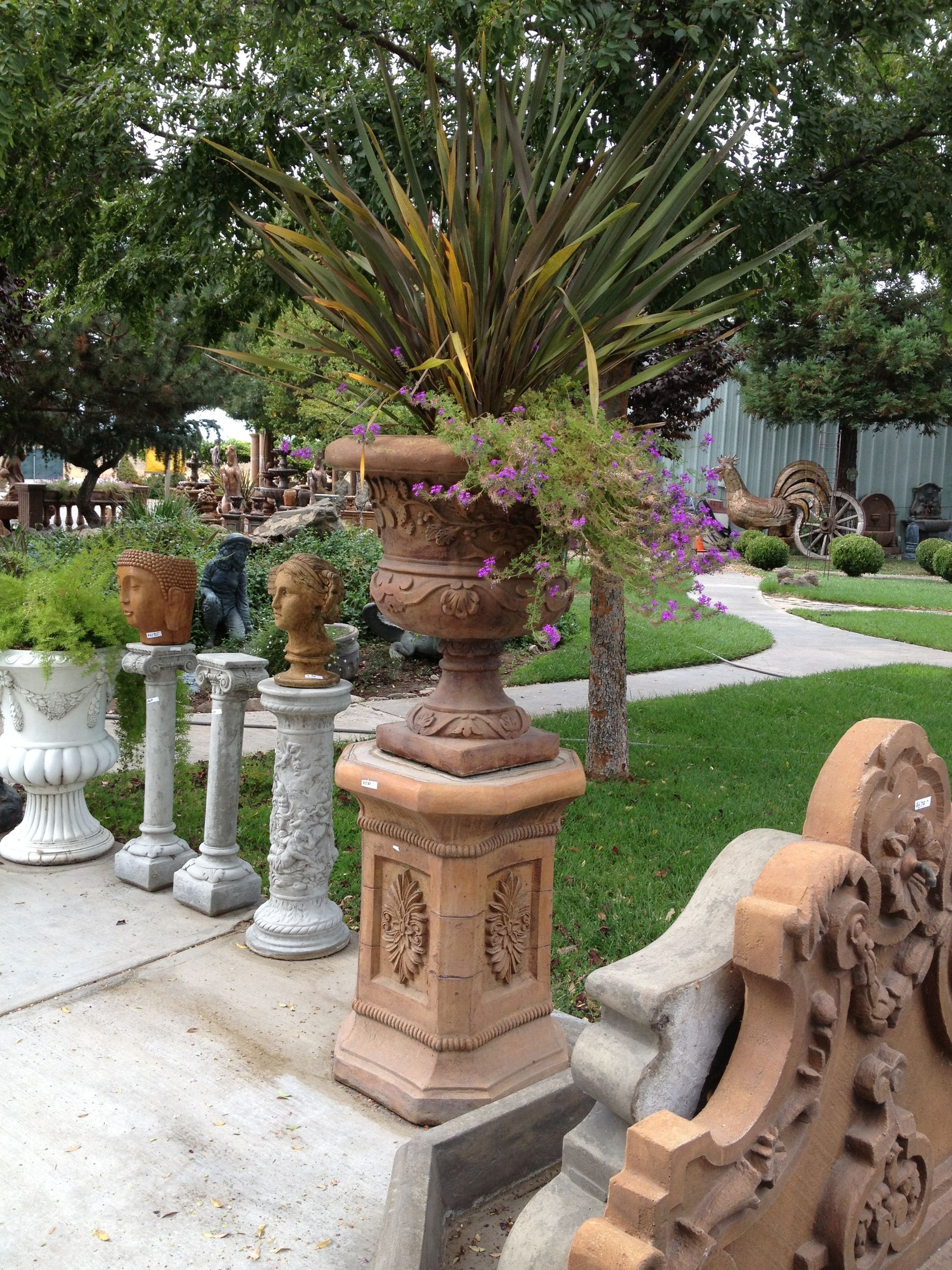 Decorative potted plants on ornate pedestals along a garden walkway
