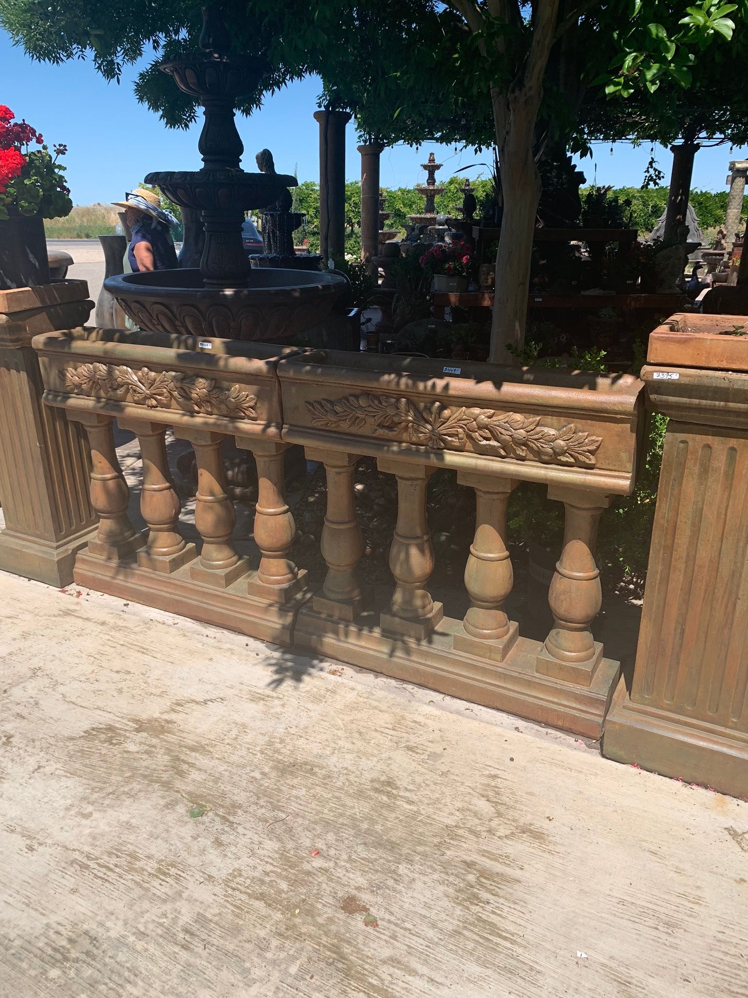 Stone balustrade beside a shaded fountain in a sunny outdoor garden area