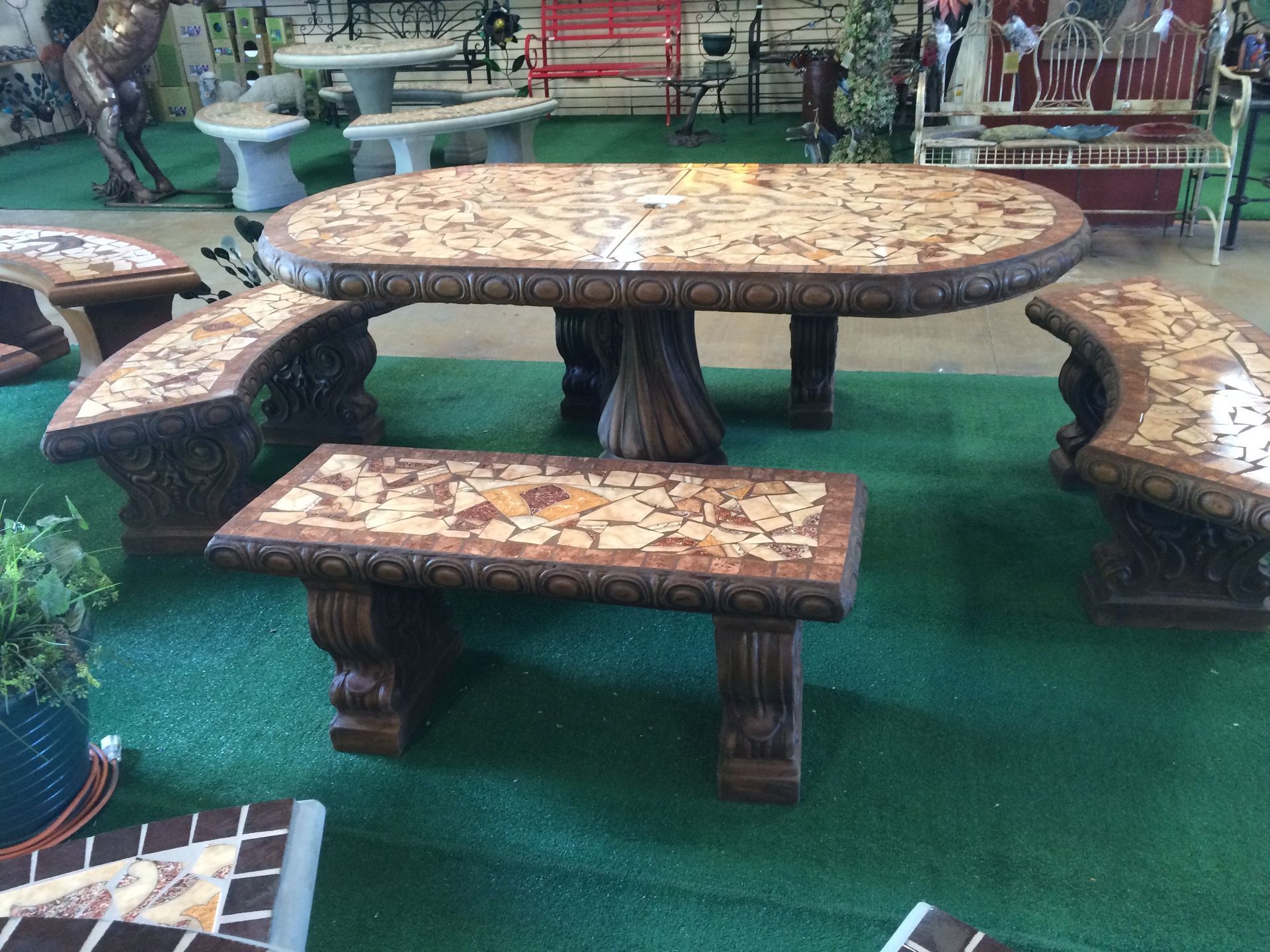 Mosaic-tiled outdoor table with matching bench seats on green turf in a garden setting