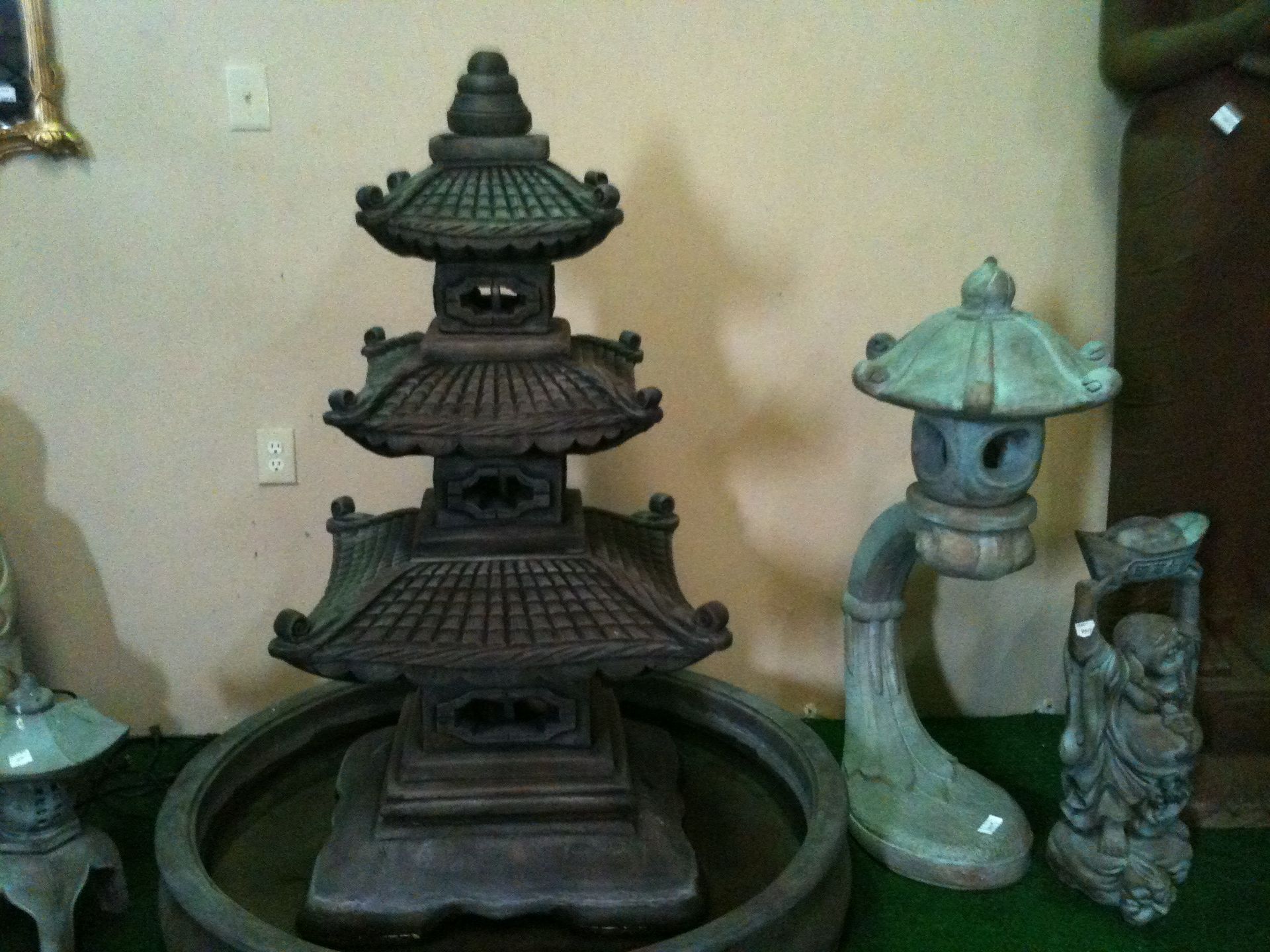 Decorative garden statues on a shelf, including a dark pagoda and two stone lanterns