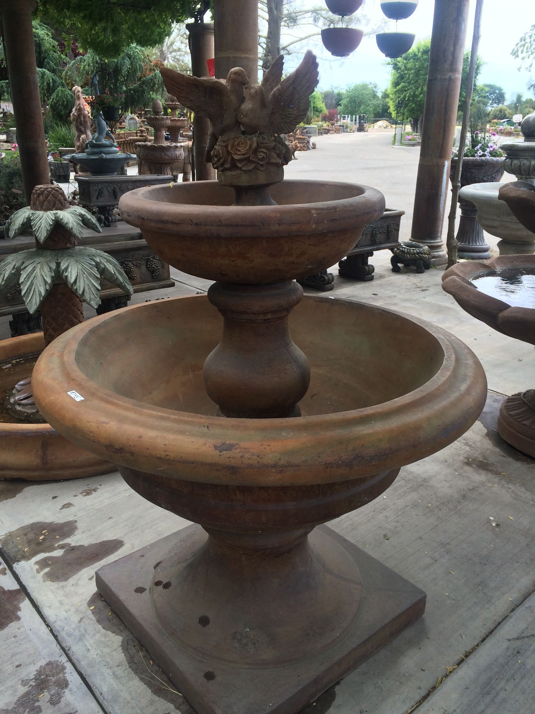 Two-tier stone fountain with a bird sculpture in a garden setting