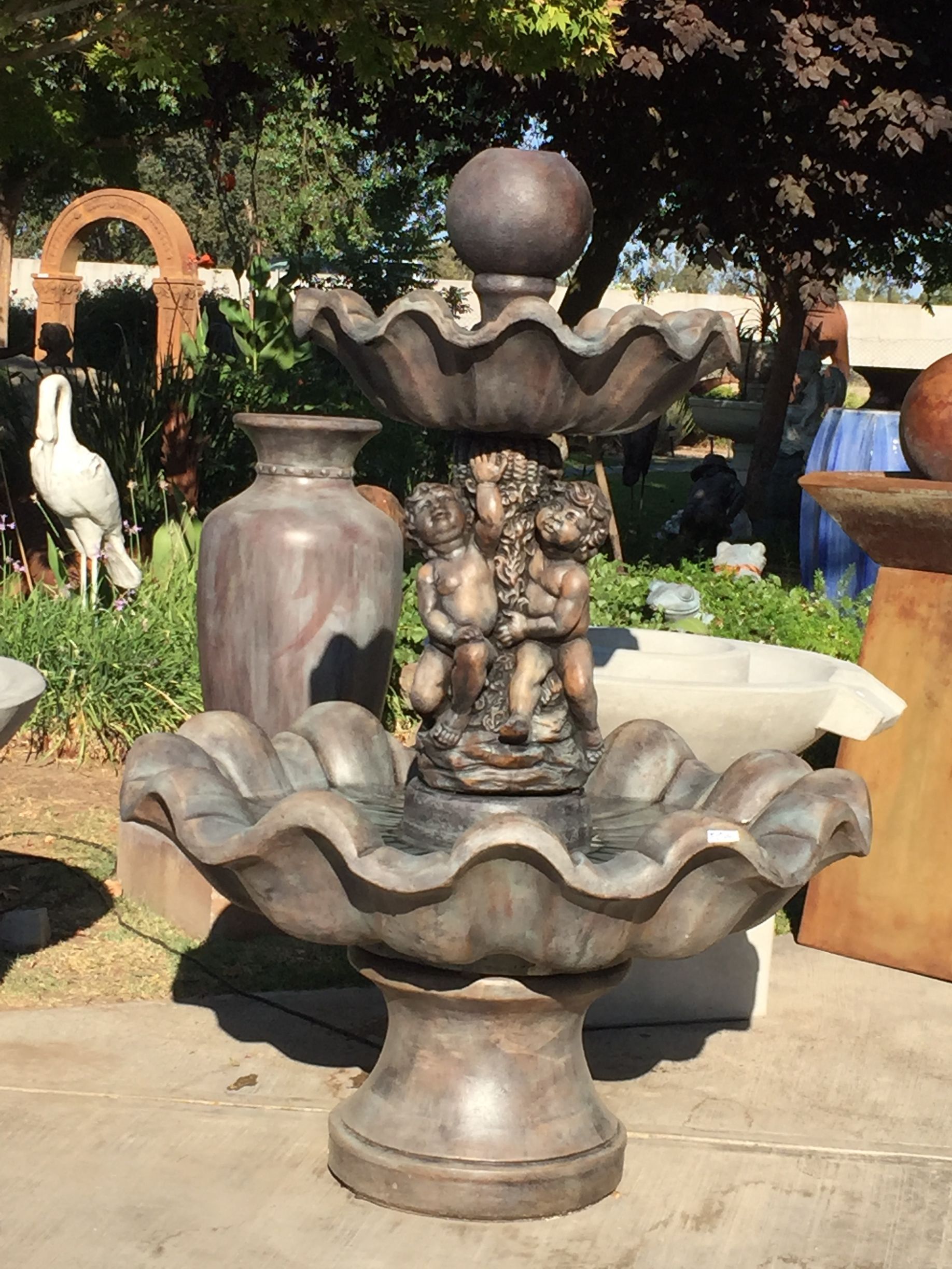 Decorative stone fountain with two basins and a ball finial in a garden setting