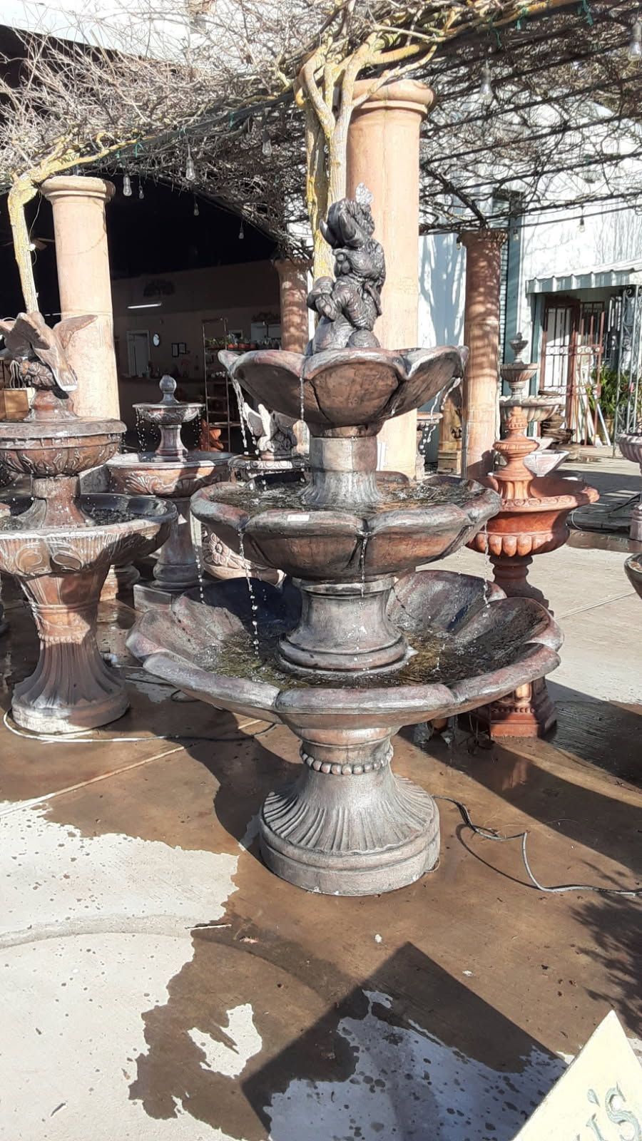 Decorative tiered stone fountain in an outdoor courtyard, with a statue at the top and water basins below