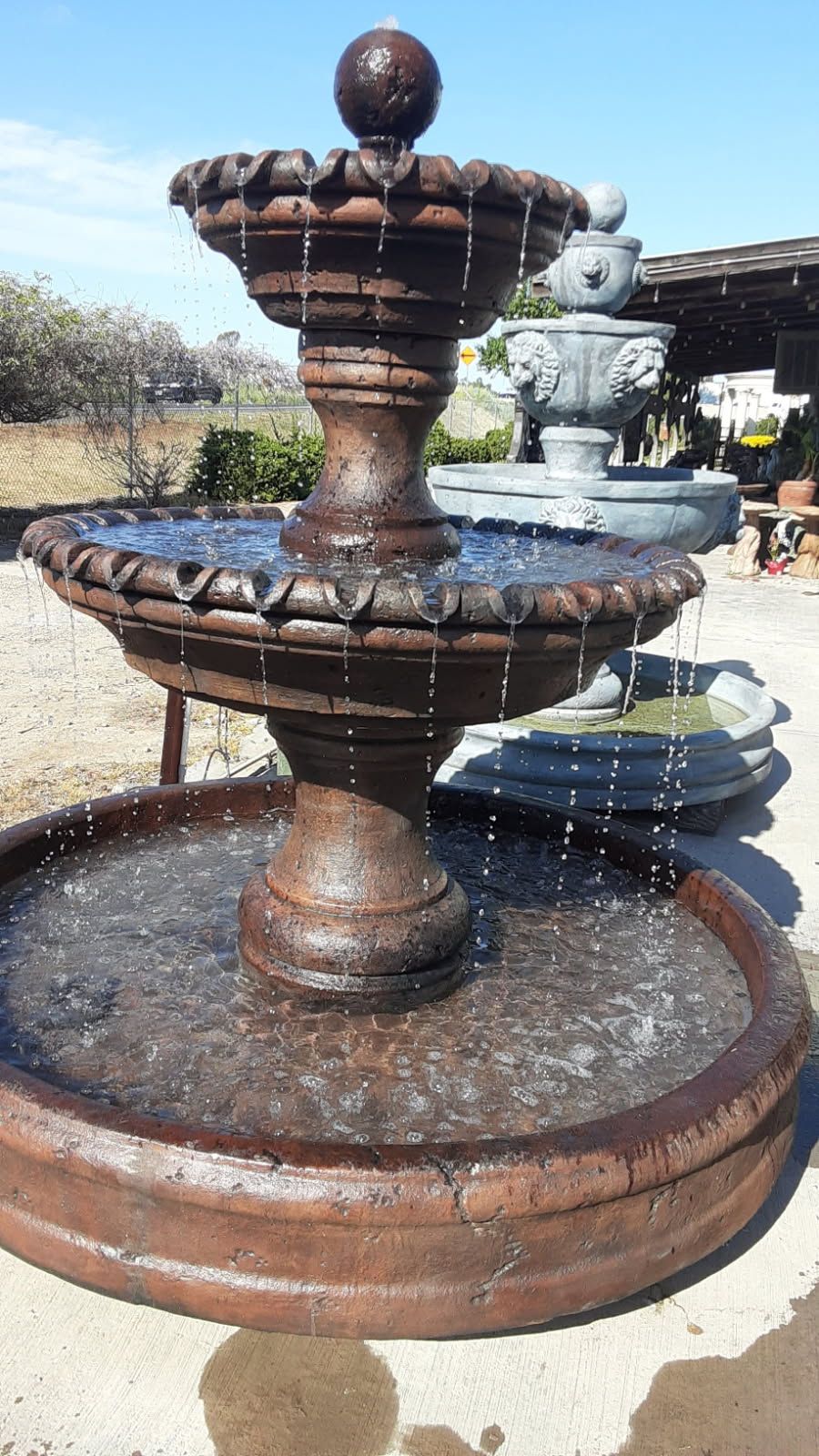 Rusty tiered stone fountain with water trickling into a round basin outdoors
