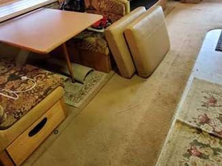 A brown table with cushioned seating and a patterned carpet in a room.