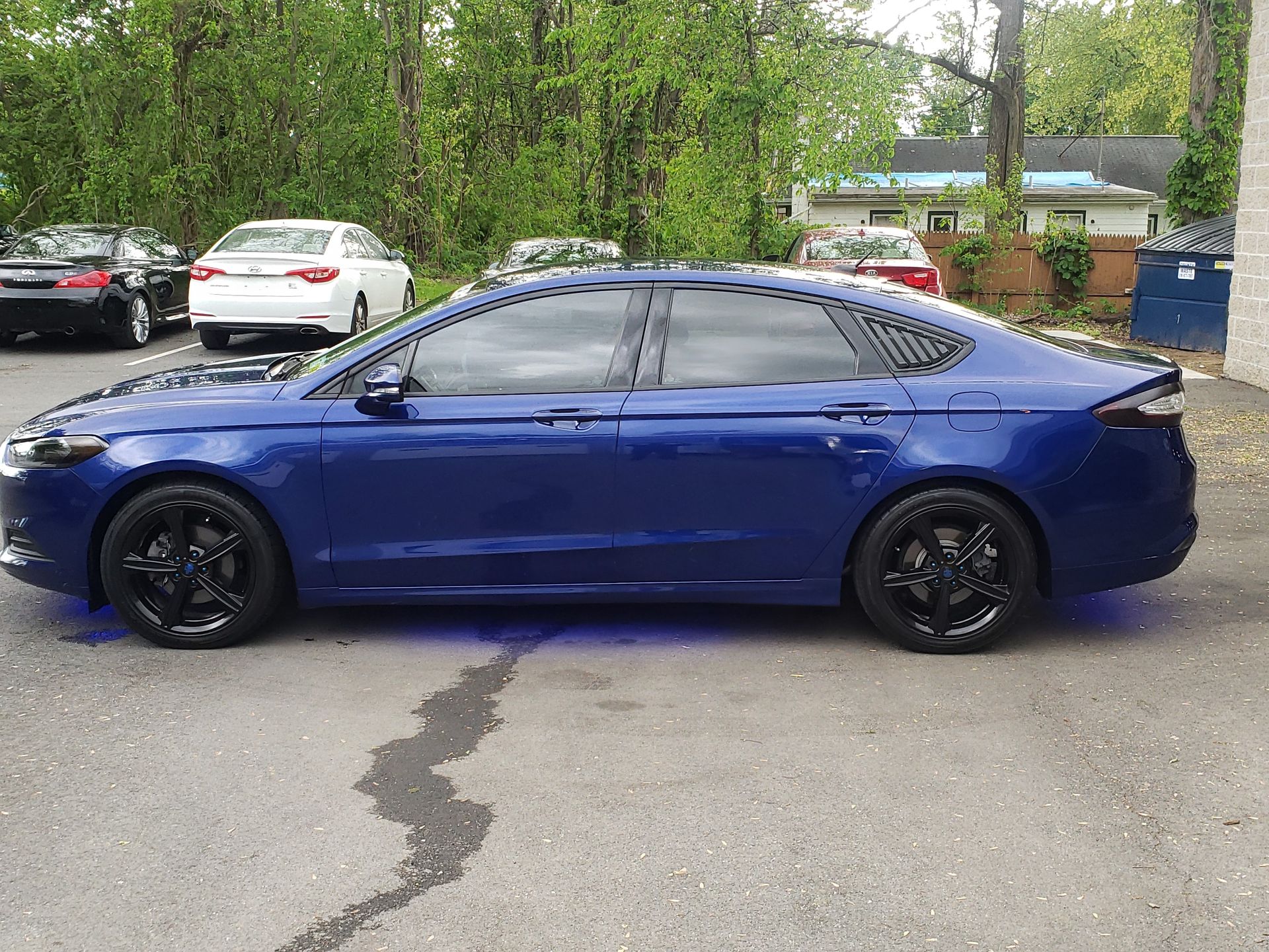 Blue Ford sedan with tinted windows, black wheels, parked outdoors.