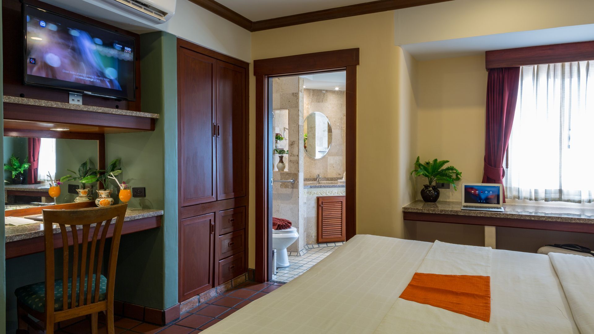 A hotel room with a bed , desk , chair and television.