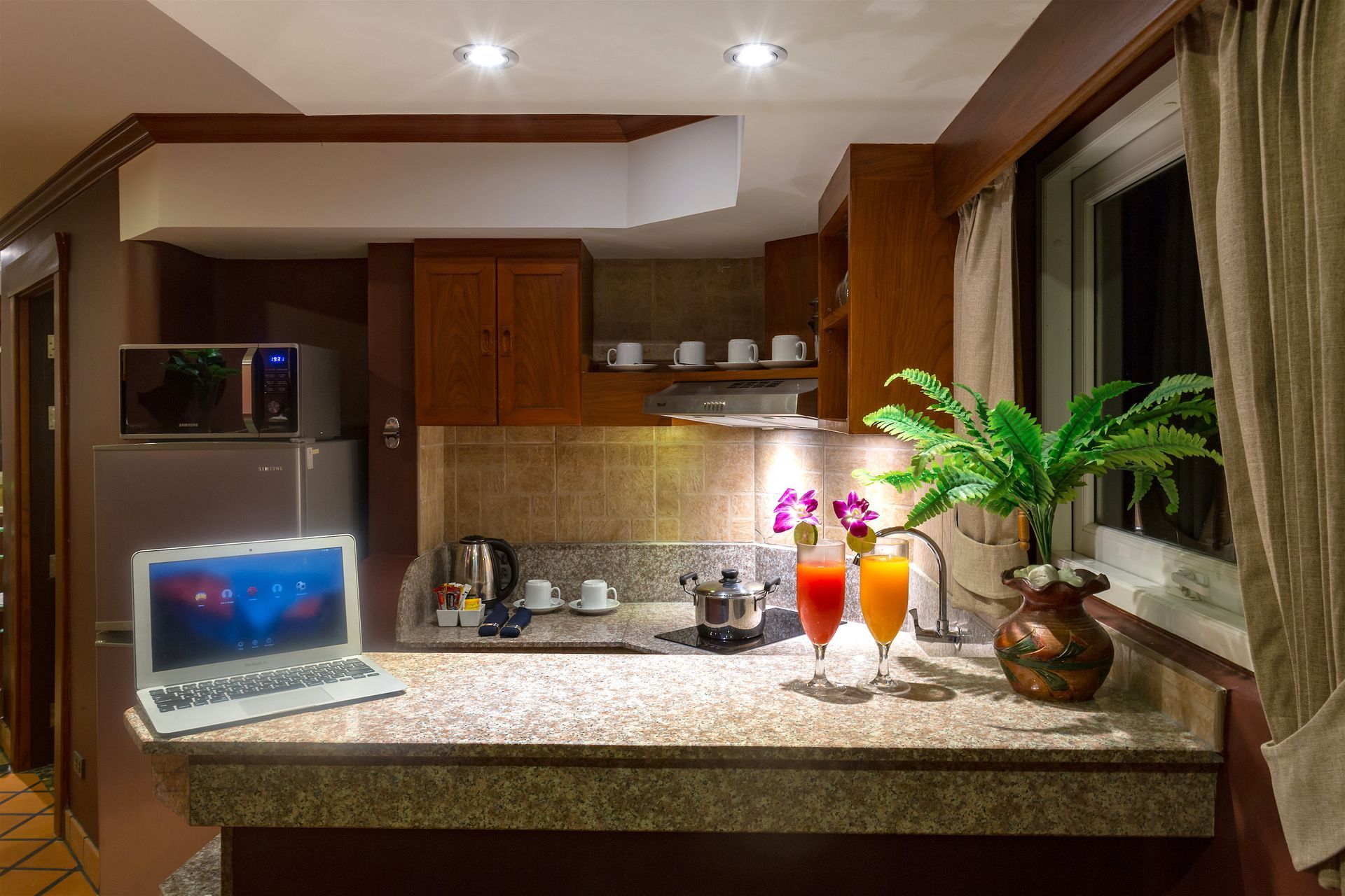 There is a laptop on the counter in the kitchen.