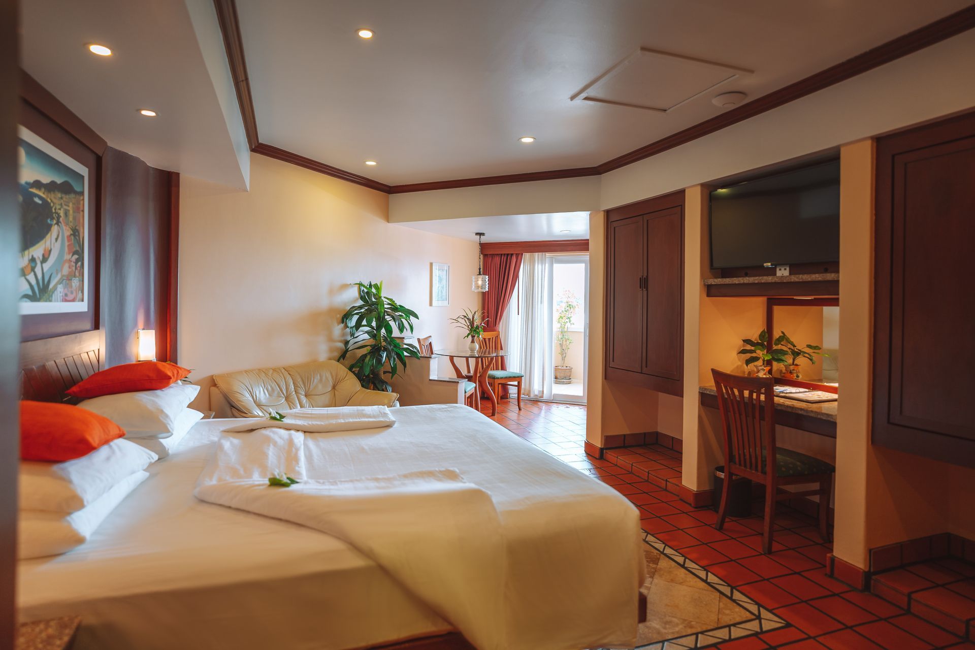 A hotel room with a large bed , couch , desk and television.