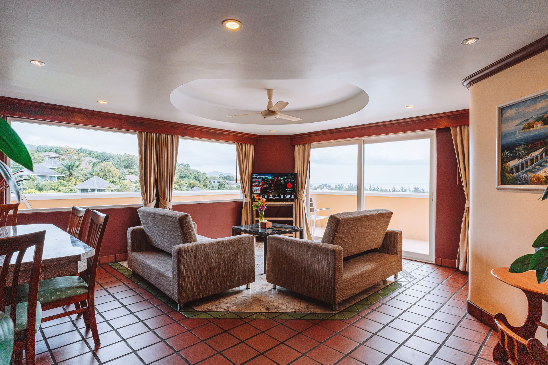 A living room with a couch , two chairs , a table and a television.