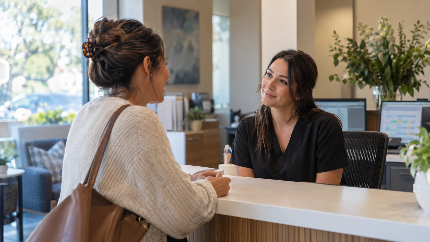 Two people talking across a counter in a bright office lobby
