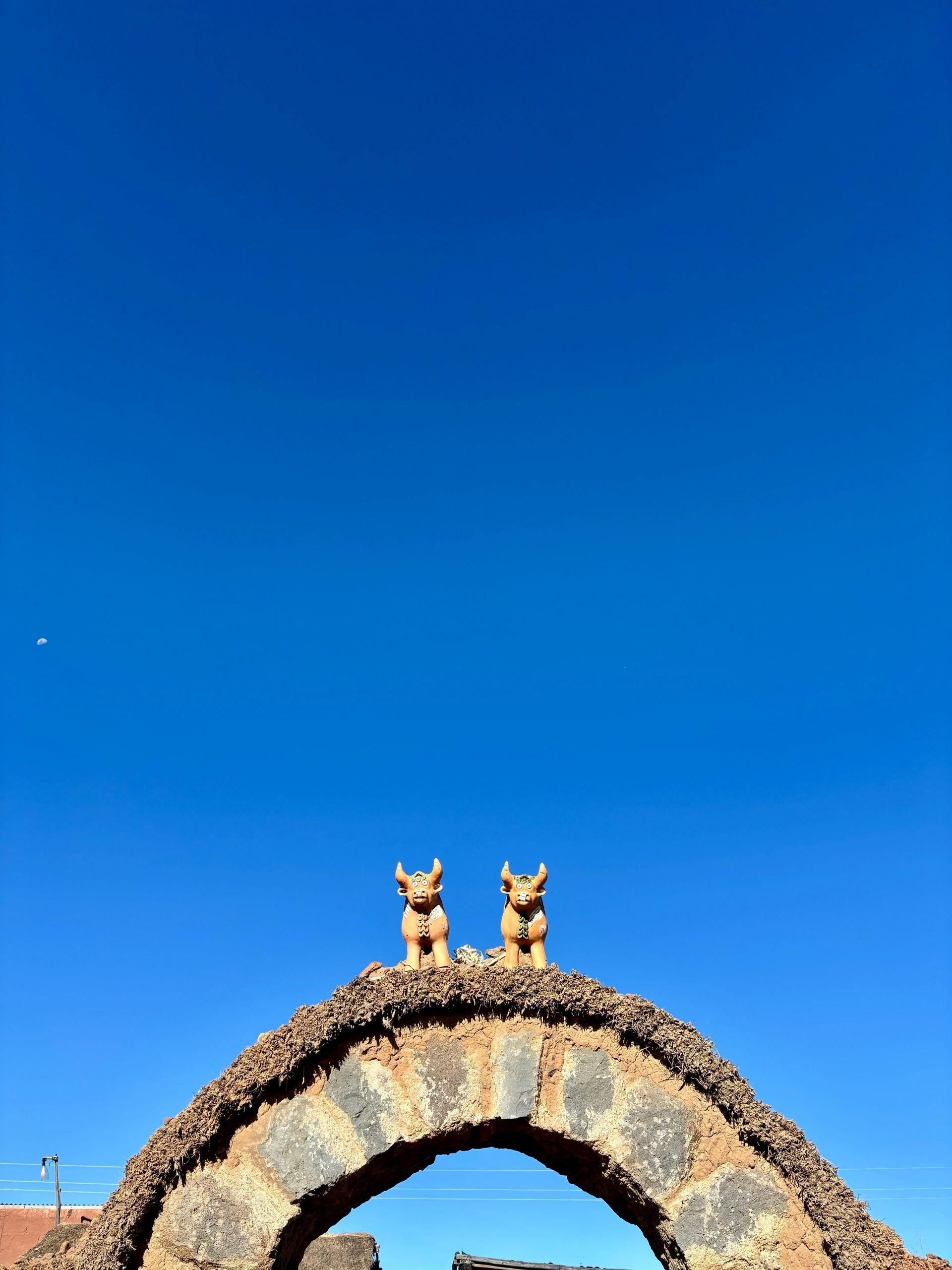 Dos estatuas de piedra que representan pequeños animales se alzan sobre un portal de piedra arqueado 