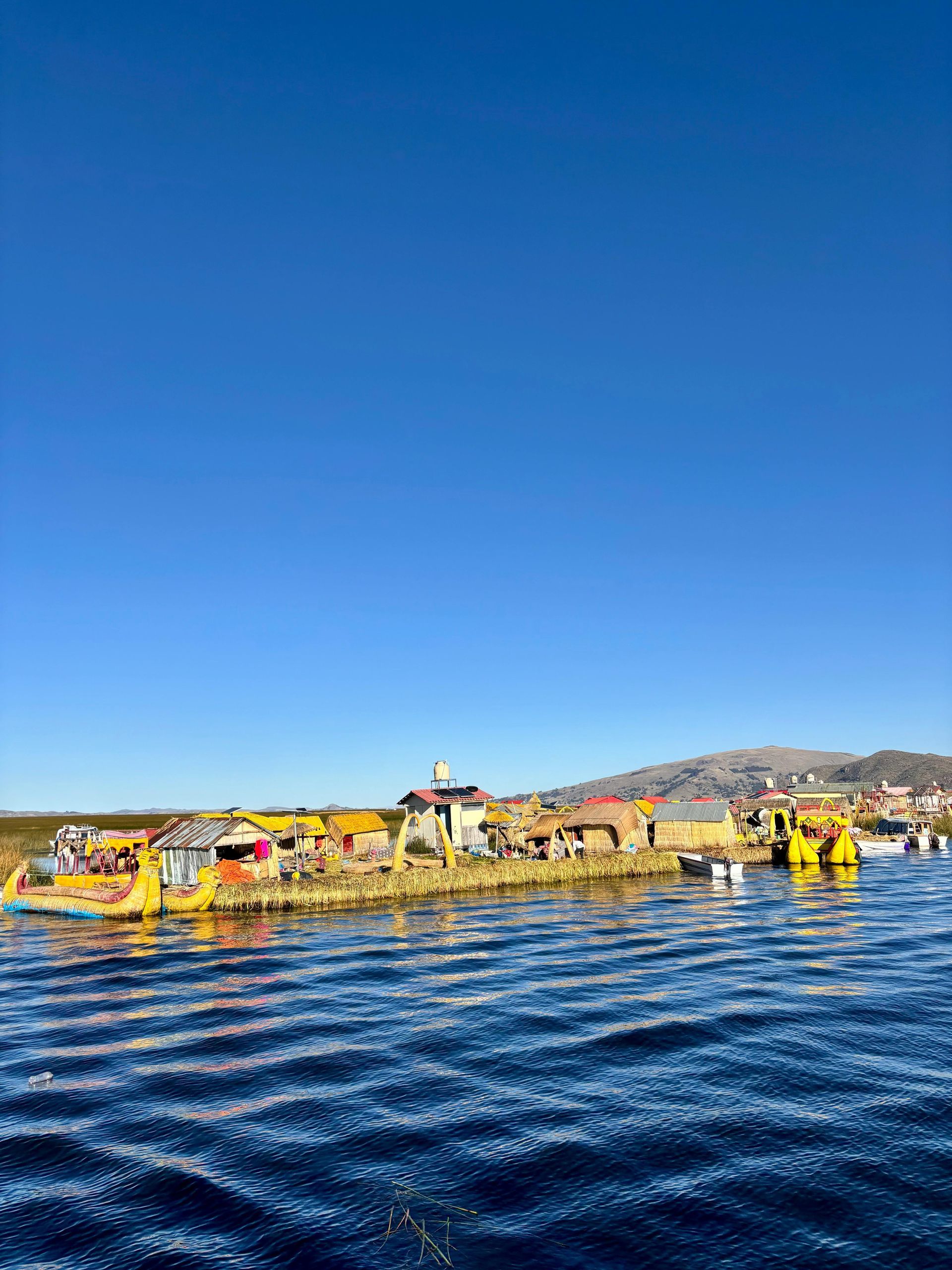 Las islas flotantes de los Uros, formadas por juncos de totora, en el lago Titicaca bajo un cielo azul despejado.