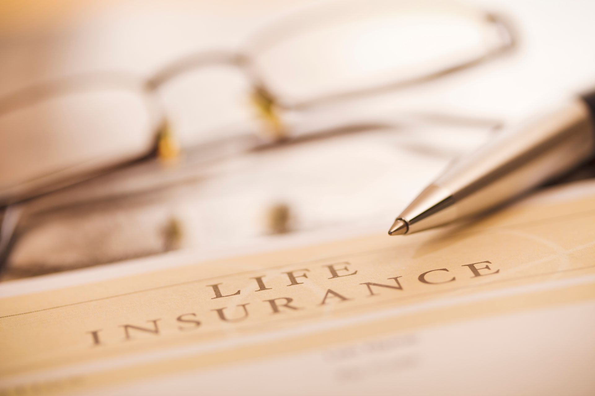 Close-up of life insurance document with pen and glasses, indicating financial planning and security.