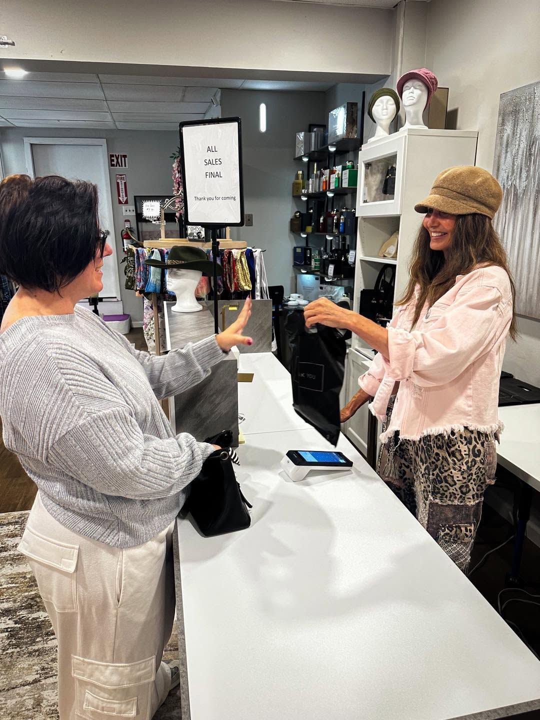 Two people exchanging an item across a white retail counter in a store.