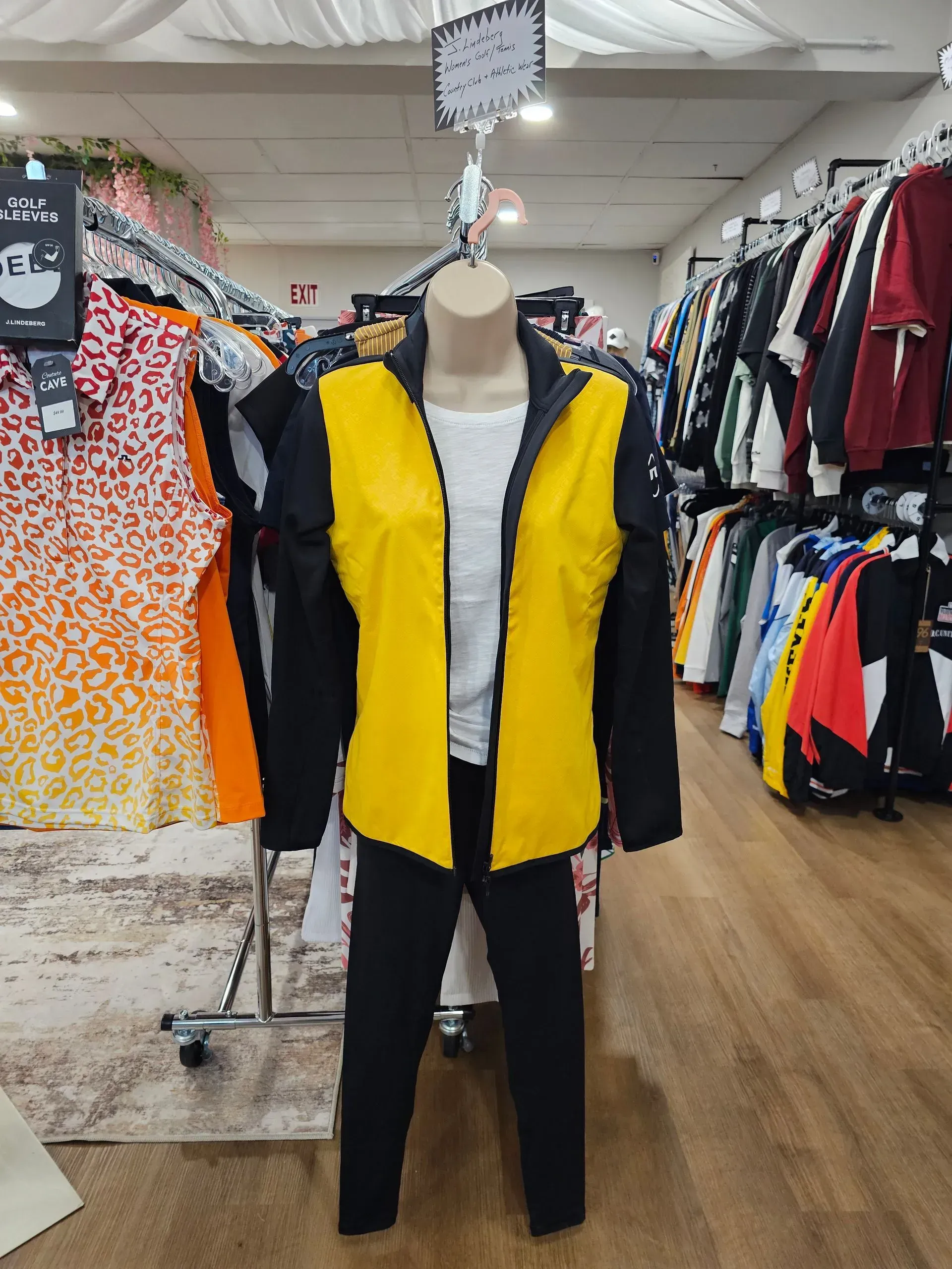 Mannequin wearing a yellow and black jacket in a clothing store aisle