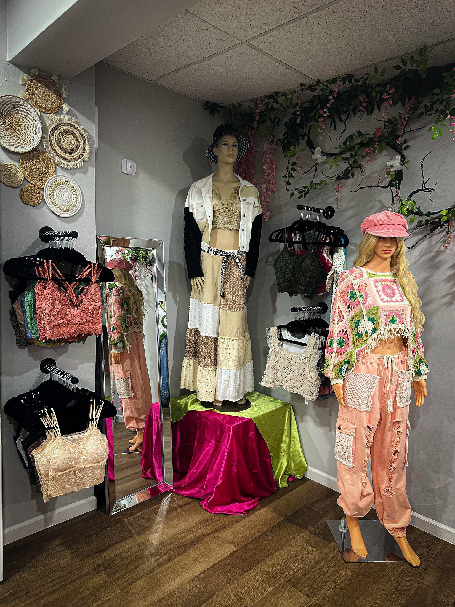 Fashion boutique display with colorful clothes, mannequins, and a woman standing beside the racks