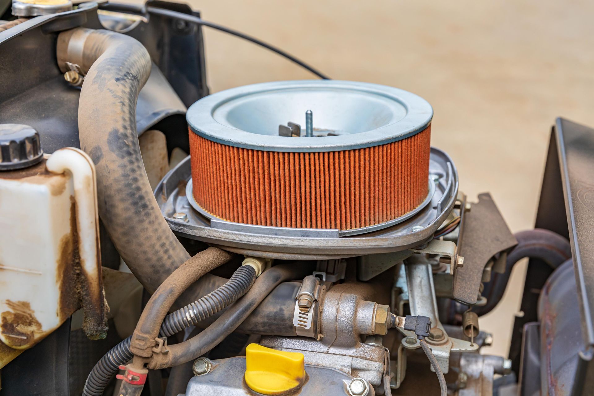 Close-up of a small engine with an orange air filter and hoses attached