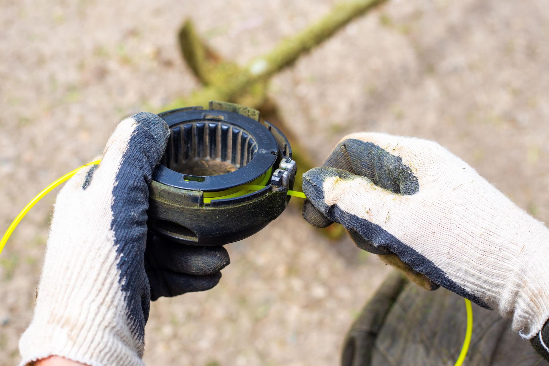 Gloved hands connecting two black electrical cable ends outdoors