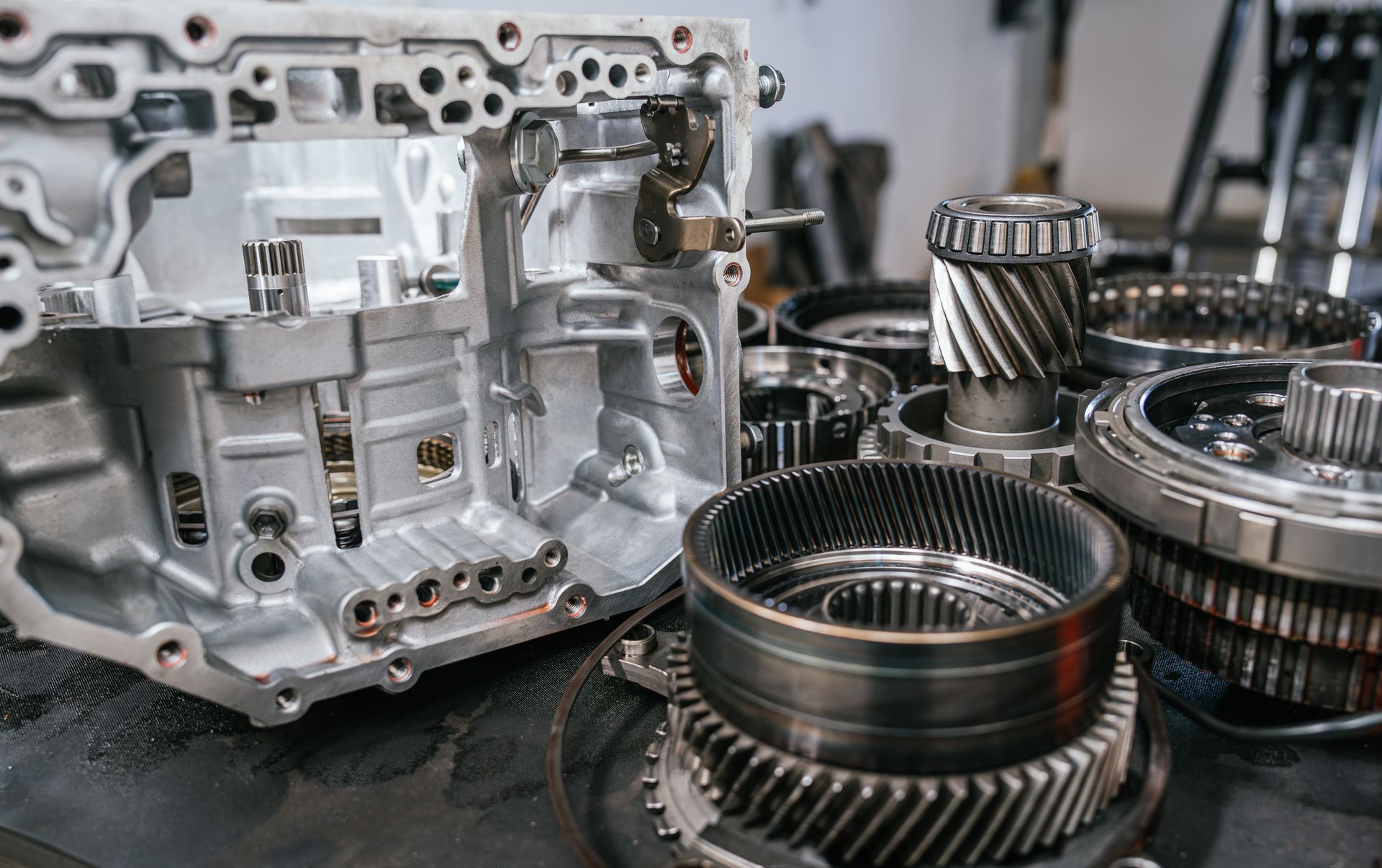 Disassembled transmission housing and metal gears laid out on a workbench