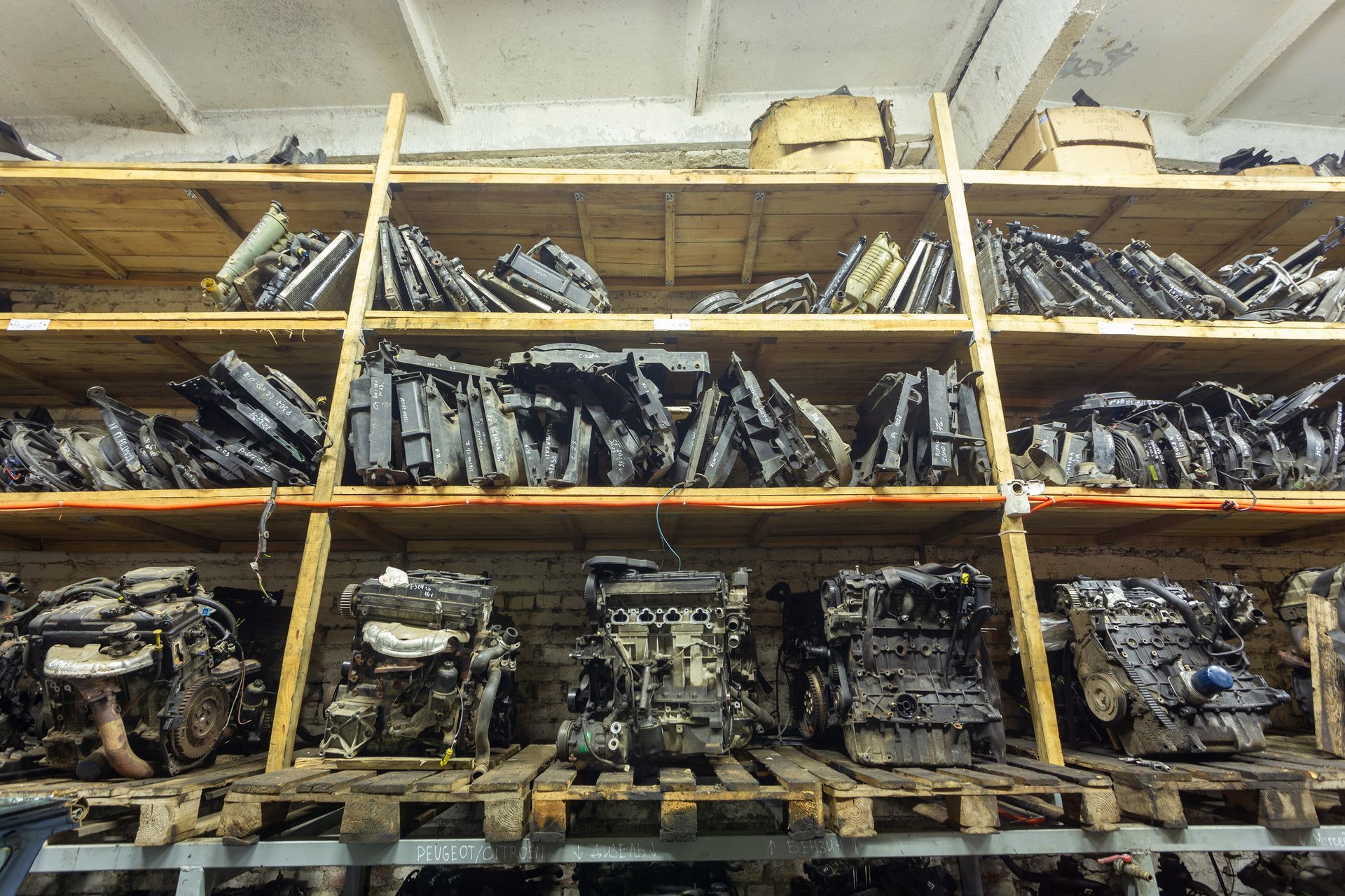 Shelves stocked with used car engines and mechanical auto parts inside a warehouse.