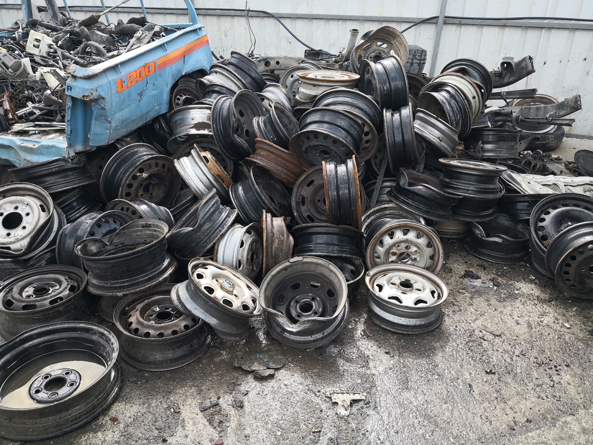 Pile of scrap steel car rims and wheels at auto recycling yard, metal waste ready for reuse USA.