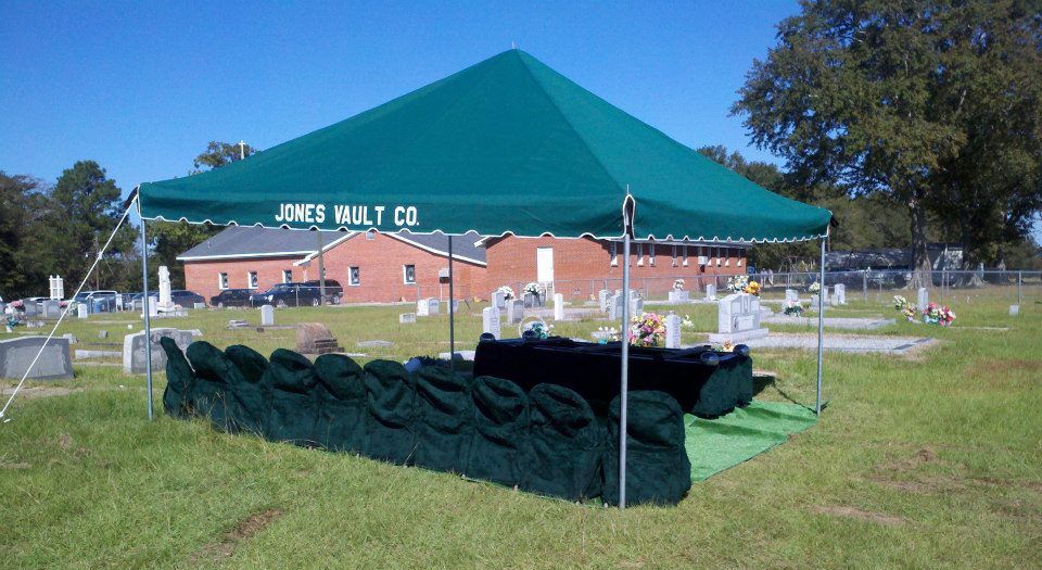 A green tent is set up in a cemetery.