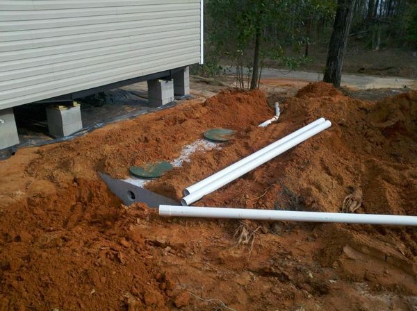 A pile of dirt and pipes in front of a house.