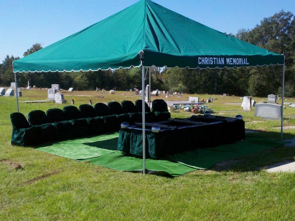 A green tent in a cemetery that says christian memorial