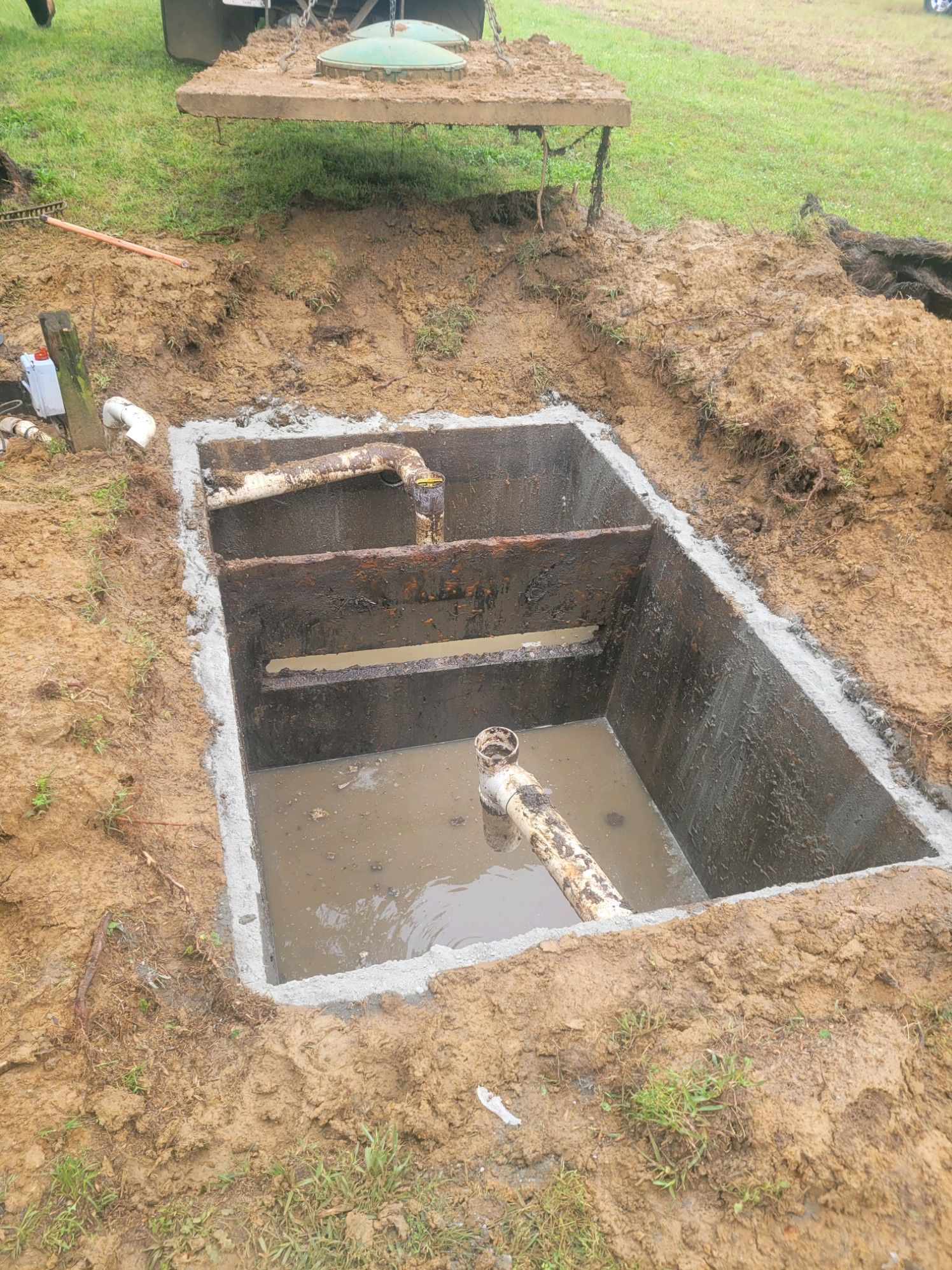 A man is pumping a hose into a septic tank.