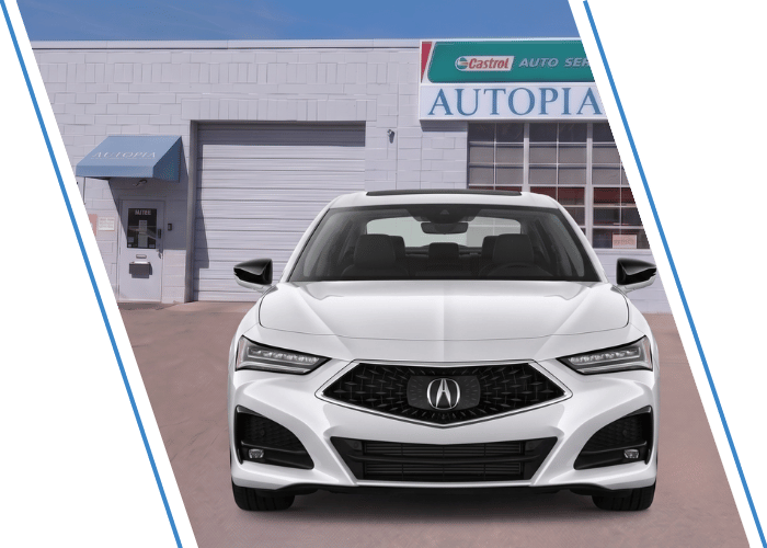 Front view of a white Acura sedan parked outside an auto repair shop.