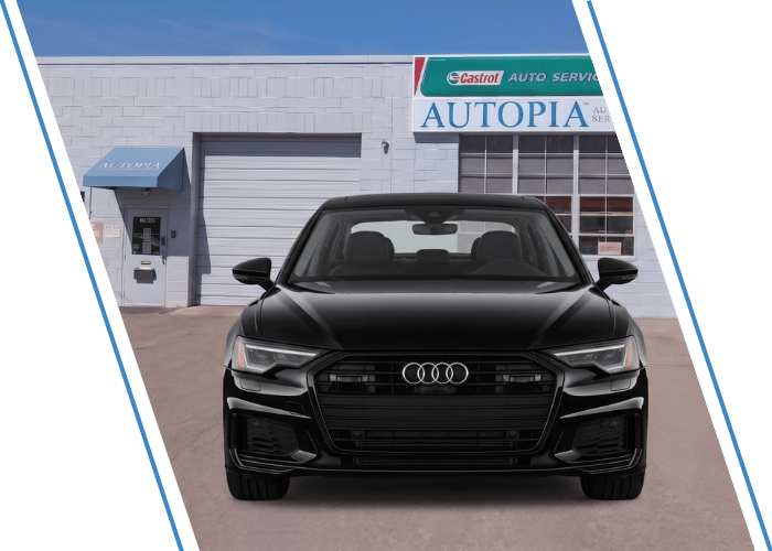 Front view of a black Audi SUV parked outside an auto repair shop.