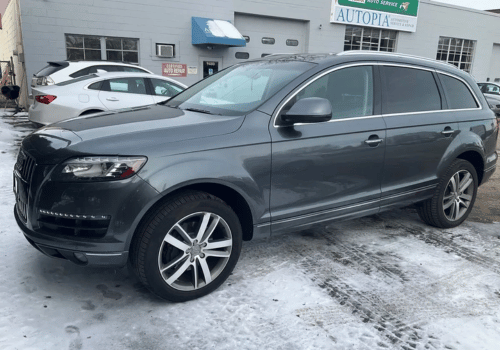Gray Audi Q7 SUV parked outside an auto repair shop on a snowy day