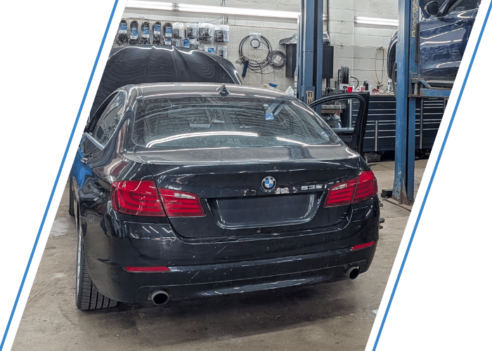 Black BMW sedan in a professional repair shop awaiting maintenance and diagnostics.