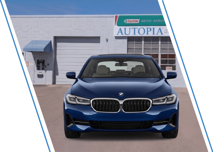 Front view of a blue BMW sedan parked outside an auto repair shop.