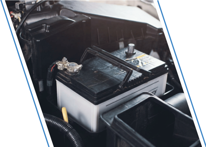 Automotive battery installed in a vehicle engine compartment.