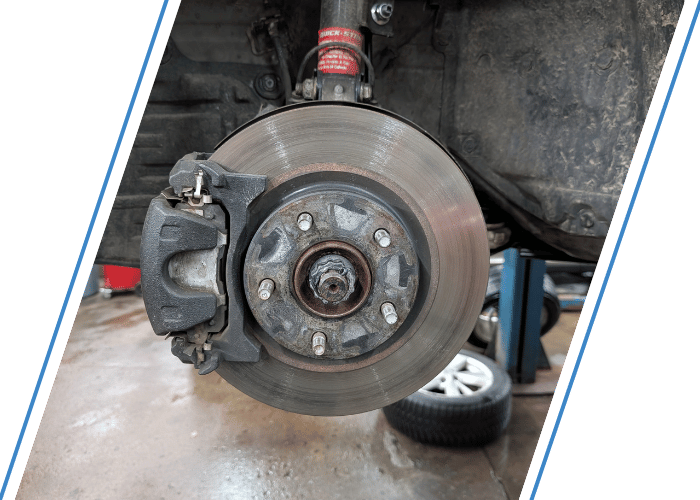 Close-up of a front brake rotor and caliper during brake inspection and repair.