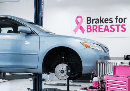 Blue Toyota Camry undergoing brake service inside an auto repair shop featuring a Brakes for Breasts