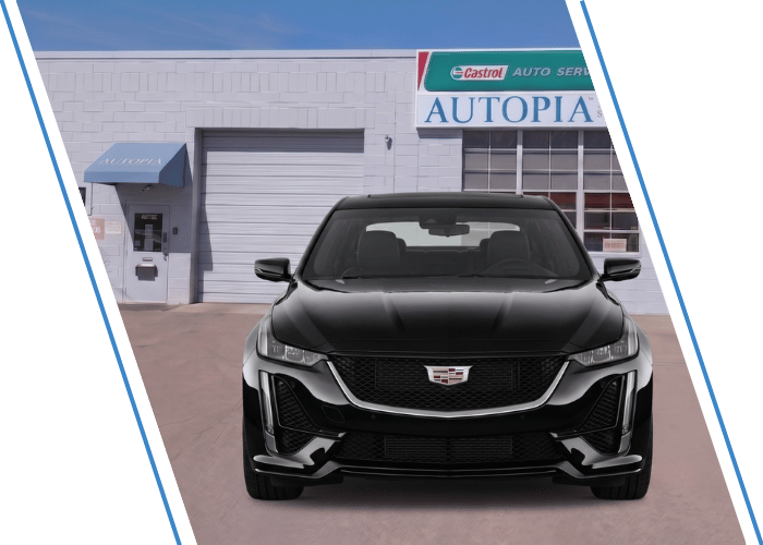 Front view of a black Cadillac SUV parked outside an auto repair shop.
