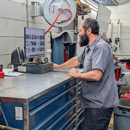 Technician using a computer at a workbench in an industrial machine shop