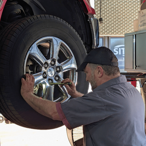 Mechanic tightening lug nuts on a car wheel with a wrench in a garage