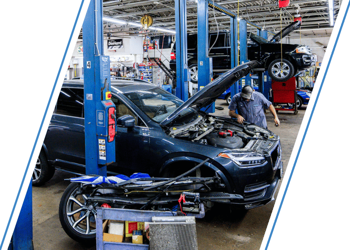 Technician performing engine diagnostics on a SUV inside a professional repair shop.