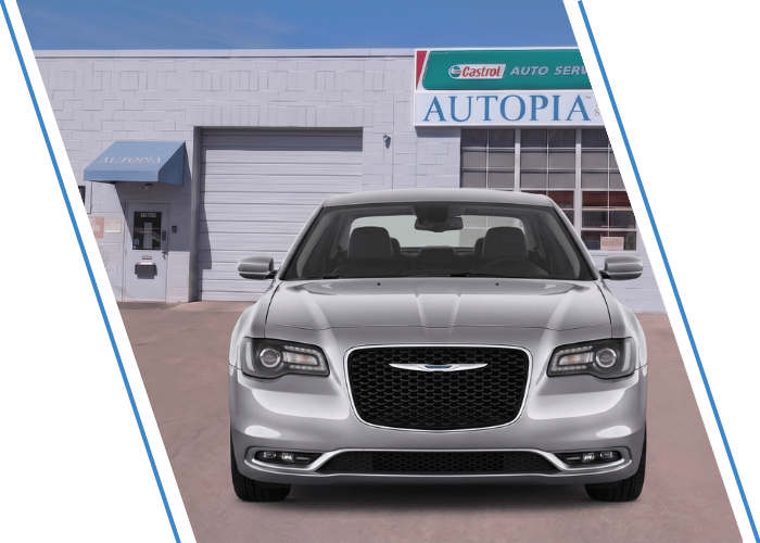 Front view of a silver Chrysler sedan parked outside an auto repair shop.