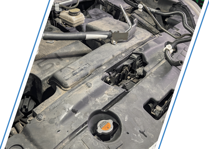 Close-up of an engine bay during cooling system service with radiator cap and coolant components visible.
